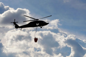 Stock photo of a UH-60 Black Hawk helitanker with a water bucket. (Image Credit: Shutterstock)